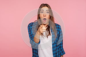 Wow, hey you! Portrait of astonished girl in checkered shirt pointing to camera, standing with surprised shocked expression