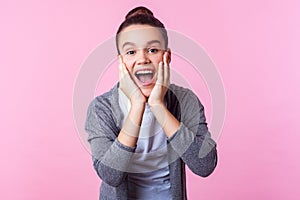 Wow, I can`t believe! Portrait of pleasantly surprised brunette teenage girl holding hands on face, shouting in amazement. indoor