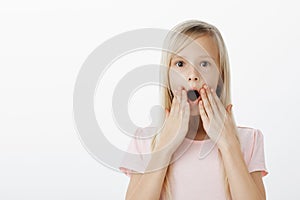 Wow, kid shocked hearing amazing news about favorite cartoon. Indoor shot of amazed and surprised happy blond daughter