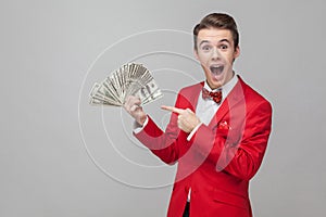 Wow, look at my money. Portrait of surprised man pointing at bunch of dollars. indoor studio shot