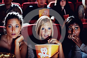 Wow, popcorn and women in the cinema watching a movie for entertainment while eating a snack. Face, expression and food