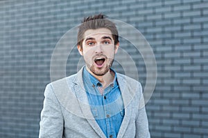 Wow. Portrait of surprised handsome bearded man in casual style standing and looking at camera with open mouth and unbelievable