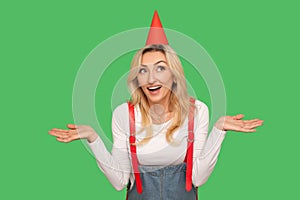 Wow, surprise! Portrait of amazed beautiful woman with funny cone on head standing with raised hands