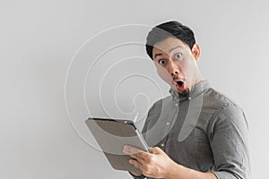 Wow and surprised entrepreneur businessman work on his tablet with grey background