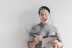 Wow and surprised entrepreneur businessman work on his tablet with grey background