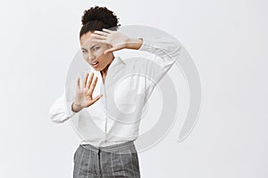 Wow, turn light off man. Disturbed and displeased african-american businesswoman in white shirt and pants, lifting hands