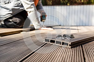 Wpc terrace construction - worker installing wood plastic composite decking boards