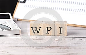 WPI word on a wooden block with clipboard and calculator
