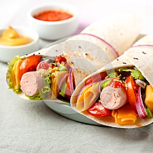 Wrap Homemade sandwich with vegetables and cheese and organic sausage on a plate. Fabric cloth textile background.