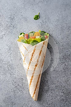 Wrap sandwich, roll with fish salmon, vegetables and cheese. Grey background. Top view.