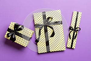 Wrapped Christmas or other holiday handmade present in paper with Black ribbon on purple background. Present box, decoration of