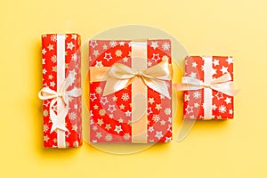 Wrapped Christmas or other holiday handmade present in paper with gold ribbon on yellow background. Present box, decoration of