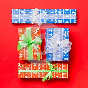 Wrapped Christmas or other holiday handmade present in paper with white and green ribbon on red background. Present box,