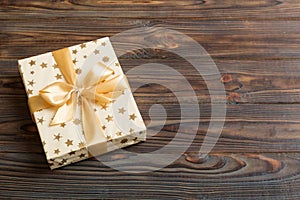 wrapped Christmas or other holiday handmade present in white paper with gold ribbon on colored background. Present box