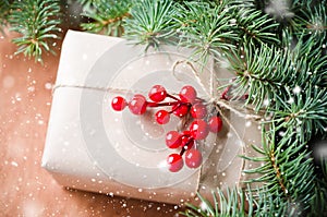 Wrapped christmas presents, fur tree branches, red berries on rustic wooden background. Drawn snow effect.