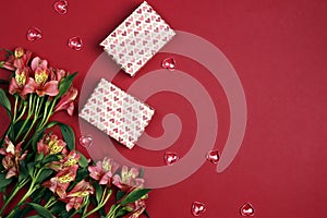 Wrapped gift boxes with alstroemeria flowers on red background