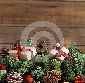 Wrapped gift boxes on reen fir branches near Christmas decorations and pine cones