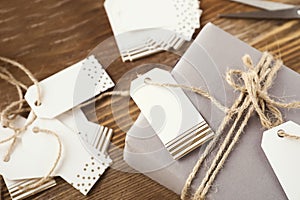 Wrapped gift and paper labels for scrapbooking on wooden background