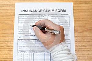 Wrapped hand filling up an insurance claim form medical and insurance concept no logo trademark