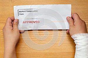 Wrapped hand holding envelope with workers compensation claim and result of approved removeable words with clipping path