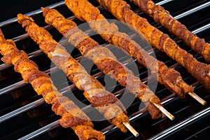 Wrapped meat spits on a cooking grate