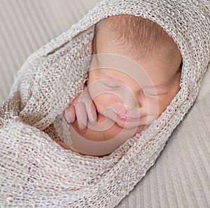 Wrapped newborn baby sleeping with smile