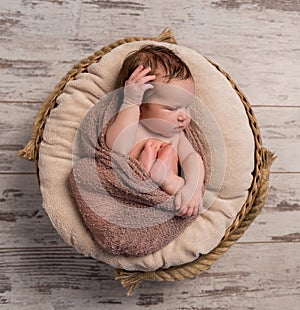 Wrapped sleepy baby with folded legs and hands on head