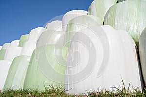 Wrapped and stacked bales of hay with blue sunny sky