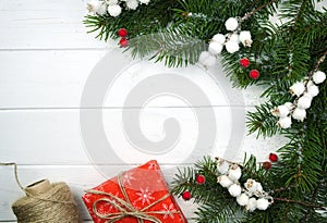 Wrapping Christmas and New Year gifts. Red gift box, twine, Christmas tree and festive decor on the white wooden background.
