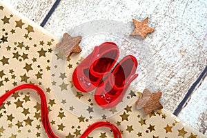 Wrapping first gift for baby for christmas , red little shoes packed in brown paper with gold stars and satin ribbon