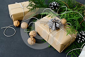Wrapping rustic eco Christmas gifts with craft paper, string and natural fir branches on dark background