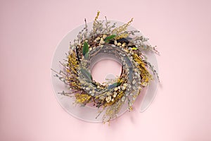 A wreath of dried twigs and flowers on a gently pink background. Natural decoration. Holiday concept. Easter wreath. Willow round