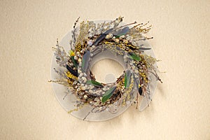 A wreath of dried twigs and flowers on a pastel background. Natural decoration. Celebration concept. Easter wreath. Willow round