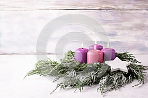 Wreath with four purple advent candles on a white background
