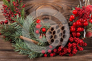 Wreath with lotus flower and red berries. Christmas winter frame on dark wooden background. Red elements