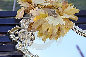 Wreath from maple leaves on a mirror in sky reflexion