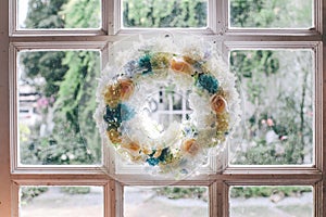 A wreath of spring flowers of blue and lilac hanging on a wooden door