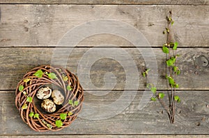 Wreath with three quail eggs and birch twigs on the old wooden t