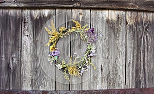 Wreath of wild flowers on the old wooden door background