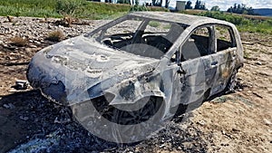 A wreck of a burnt car by the river