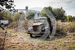 Wreck of old rusty truck in tall grass