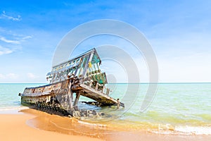 The wreckage of the fishing boat is beached  with blue sea and the blue sky as background.location Satheep Thailand