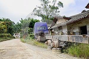 Wreckage of truck before weedy ruins of old Chinese houses