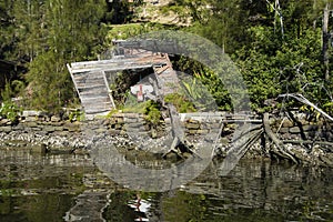 Wrecked boat in a derelict boat house refelection river