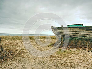 Wrecked fishing boat on old dry grass. Abandoned wooden ship with damaged engine