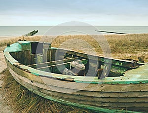 Wrecked fishing boat on old dry grass. Abandoned wooden ship with damaged engine