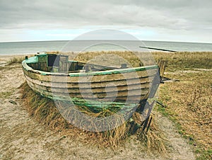 Wrecked fishing boat on old dry grass. Abandoned wooden ship with damaged engine