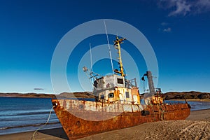 A wrecked ship on a sandy beach at low tide in the Teriberskaya Bay. Far North, Barents Sea in Russia