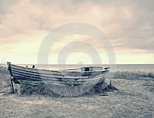 Wrecked wooden fisher boat. Broken abandoned boat in sand of sea bay.