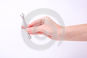 A wrench in the hand of a girl. Symbol of hard work, feminism and labor day. Isolate on white background